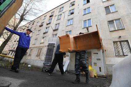 Москва. Мужчины выносят вещи из подъезда дома на Полярной улице.