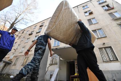 Москва. Мужчины выносят вещи из подъезда дома на Полярной улице.