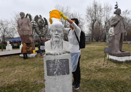 Москва. Молодой человек на общегородском субботнике `За чистоту икусства` в парке `Музеон` моет памятник Владимиру Ленину.