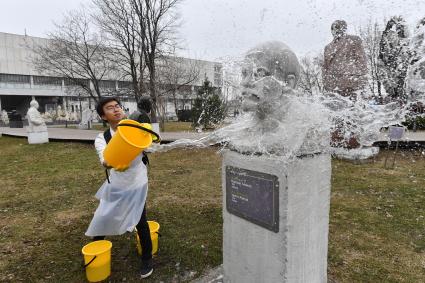 Москва. Молодой человек во время общегородского субботника `За чистоту икусства` в парке `Музеон` моет памятник Владимира Ленина.