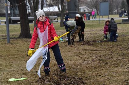 Москва. Девочка  на общегородском субботнике `За чистоту икусства` в парке  `Музеон` убирает сухие листья с газона.