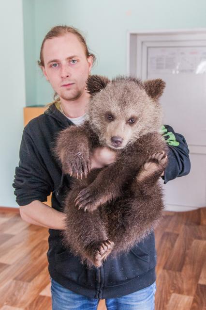 Уфа. Мужчина держит на руках бурого медвежонка, родившегося в вольере в парке Лесоводов.