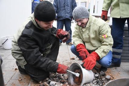 Москва.  Мастера-литейщики на площади Революции  в открытой литейной мастерской отливает колокол в рамках фестиваля `Пасхальный дар`.