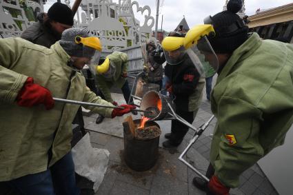 Москва.  Мастера-литейщики на площади Революции  в открытой литейной мастерской отливает колокол в рамках фестиваля `Пасхальный дар`.