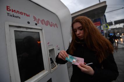 Москва.  Девушка с социальной картой москвича у платежного терминала Мосгортранса.