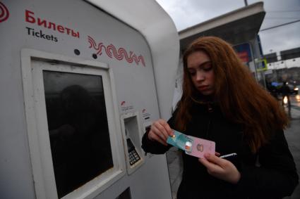 Москва.  Девушка с социальной картой москвича у платежного терминала Мосгортранса.