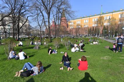 Москва. Молодые люди сидят на газоне  в Александровском саду.