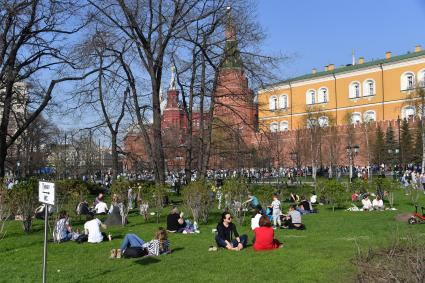 Москва. Молодые люди сидят на газоне в Александровском саду.