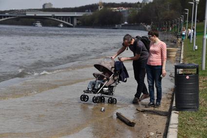 Москва. Семья с ребенком в коляске  гуляет по  затопленной   набережной  на Воробьевых горах.