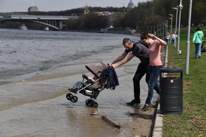 Москва. Семья с ребенком в коляске  гуляет по  затопленной   набережной  на Воробьевых горах.