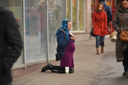 Москва.  Беременная женщина просит милостыню у прохожих на одной из улиц города.