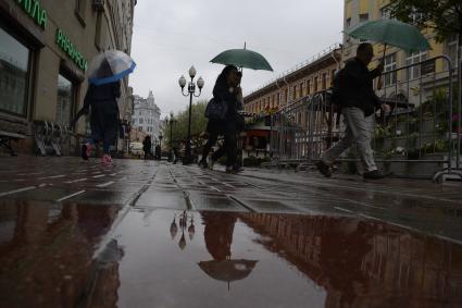 Москва.  Прохожие под дождем идут по Старому Арбату.