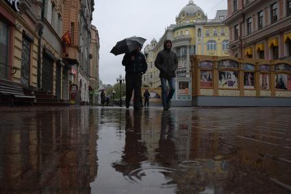 Москва.  Прохожие под дождем идут по Старому Арбату.