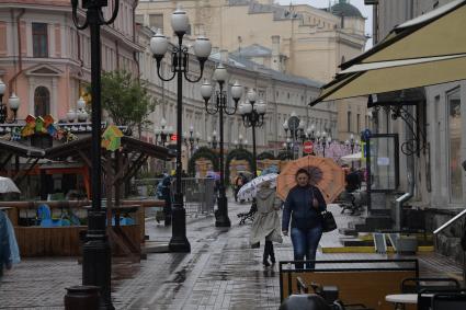 Москва.  Прохожие под дождем идут по Старому Арбату.