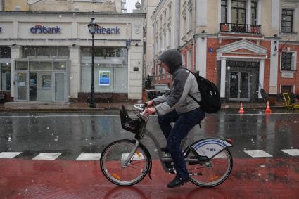 Москва.  Велосипедист под снегом на Большой Никитской улице.