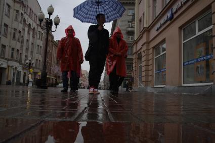 Москва.  Прохожие под дождем идут по Старому Арбату.