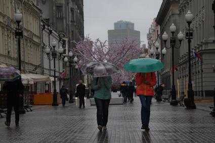 Москва.  Прохожие под дождем идут по Старому Арбату.