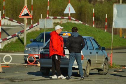 Ектеринбург. Автодром ДОСААФ. Курсант с инструктором по вождению у учебного автомобиля на площадке по подготовки водителей категории \'Б\'