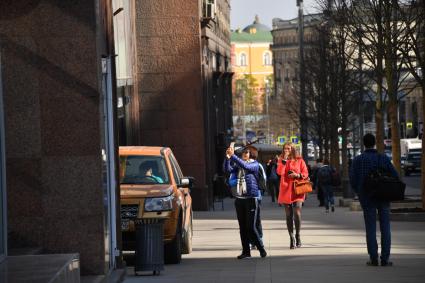 Москва. Девушка фотографируется на Тверской улице.