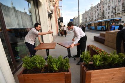 Москва. Мужчины устанавливают столики  для уличного кафе.