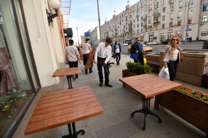 Москва. Мужчины устанавливают столики  для уличного кафе.