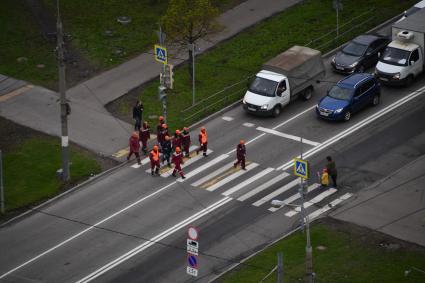 Москва.  Рабочие переходят дорогу по пешеходному переходу в районе Бескудниково.