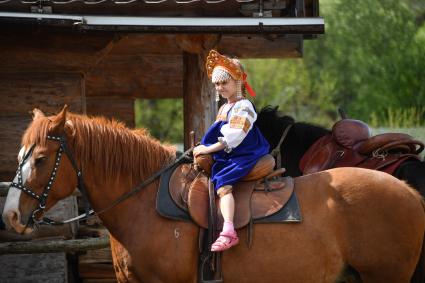 Московская область. Слобода Германа Стерлигова.  Девочка в русском народном костюме сидит на лошади.