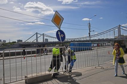 Москва. Рабочие укрепляют  дорожный знак на Пречистенской набережной.