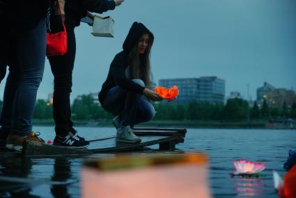 Екатеринбург. Девушка запускают водный фонарик на набережной городского пруда. Фестиваль водных фонариков