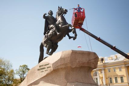 Санкт-Петербург.   Сотрудники Службы по текущему уходу и содержанию памятников СПбГУ `Государственного музея городской скульптуры` во время мытья  памятника Петру I `Медный всадник`  на Сенатской площади.