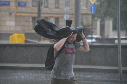 Москва. Молодой человек во время урагана на одной из улиц города.