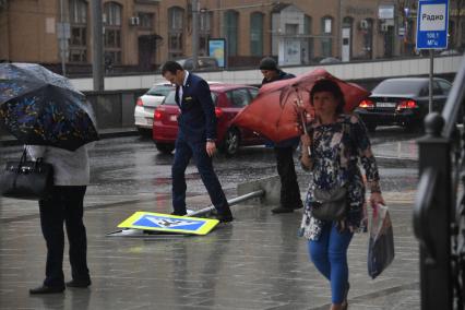 Москва.   Поваленный ураганом дорожный знак на одной из улиц города.