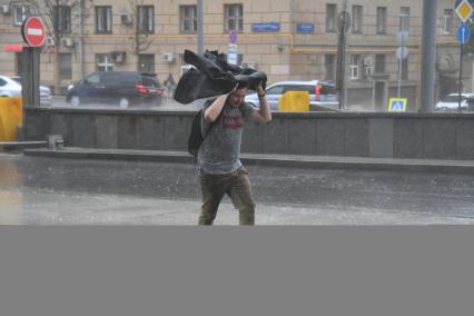 Москва. Молодой человек во время урагана на одной из улиц города.