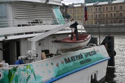 Москва. Рабочий в лодке поднимается на борт теплохода `Валерий Брюсов` , на котором идет демонтаж оборудования.