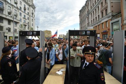 Москва. Полицейские пропускают людей через рамки металлоискателя.