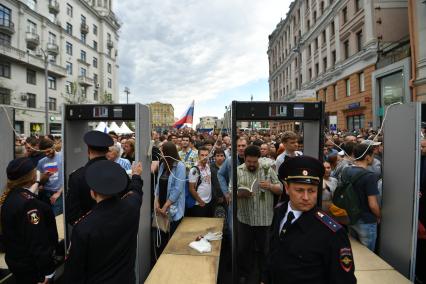 Москва. Полицейские пропускают людей через  рамки металлоискателя.