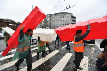 Москва. Гастарбайтеры несут пластиковые дорожные барьеры во время ремонта дороги у метро `Баррикадная`.