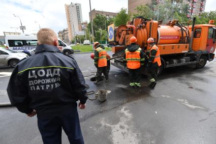 Москва.  Сотрудник дорожной службы ЦОДД  наблюдает за работой сотрудников ГУП `Мосводосток`   на Сущевском валу.