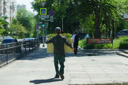 Екатеринбург. Иностранный рабочий (гастарбайтер) несет ящик с цветами