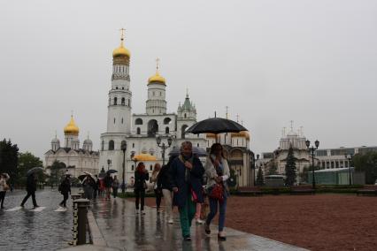 Москва. Туристы под зонтами на Ивановской площади  в Кремле.