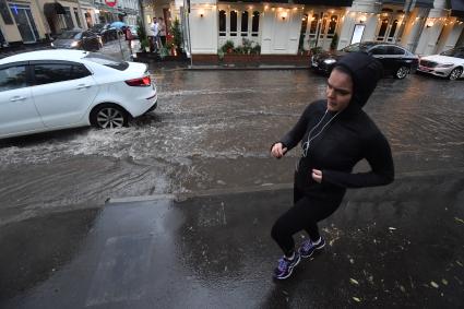 Москва. Девушка совершает пробежку по Малой Бронной во время дождя.