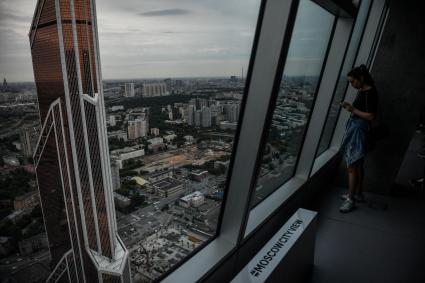 Москва.  Девушка у панорамного окна  башни `Империя `в деловом комплексе `Москва-сити`, где открылся музей, посвященный архитектурному облику города.