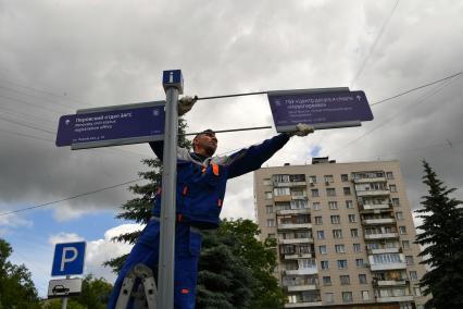 Москва. Рабочий устанавливает уличный указатель на Перовской улице.