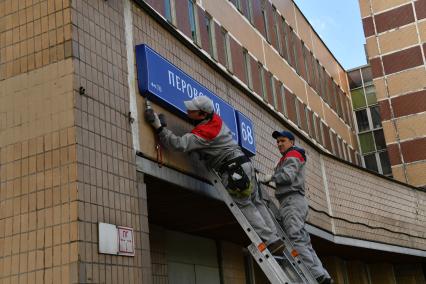 Москва. Рабочие устанавливают домовой указатель на здании Перовской улицы.