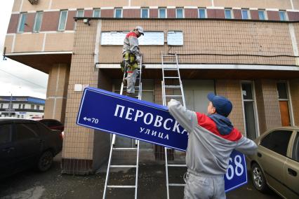 Москва. Рабочие устанавливают домовой указатель на здании Перовской улицы.