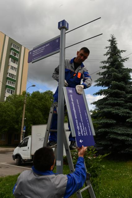 Москва. Рабочие устанавливают уличный указатель на Перовской улице.