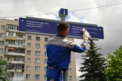 Москва. Рабочий устанавливает уличный указатель на Перовской улице.