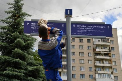 Москва. Рабочий устанавливает уличный указатель на Перовской улице.