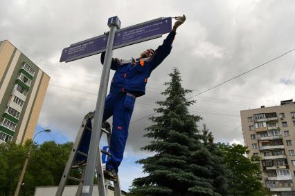 Москва. Рабочий устанавливает уличный указатель на Перовской улице.