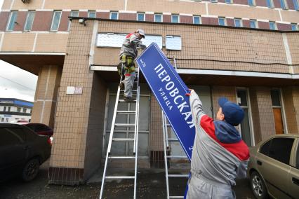 Москва. Рабочие устанавливают домовой указатель на здании Перовской улицы.